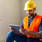 Firefly A craftsman in construction gear (helmet, boots, vest) looking proudly at his tablet showing
